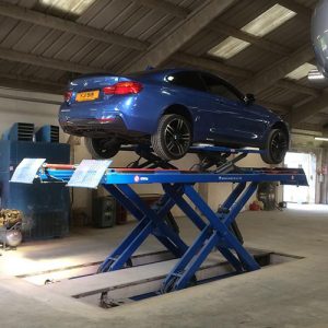 Blue BMW on scissor lift rear side view