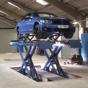 Blue BMW on scissor lift front view